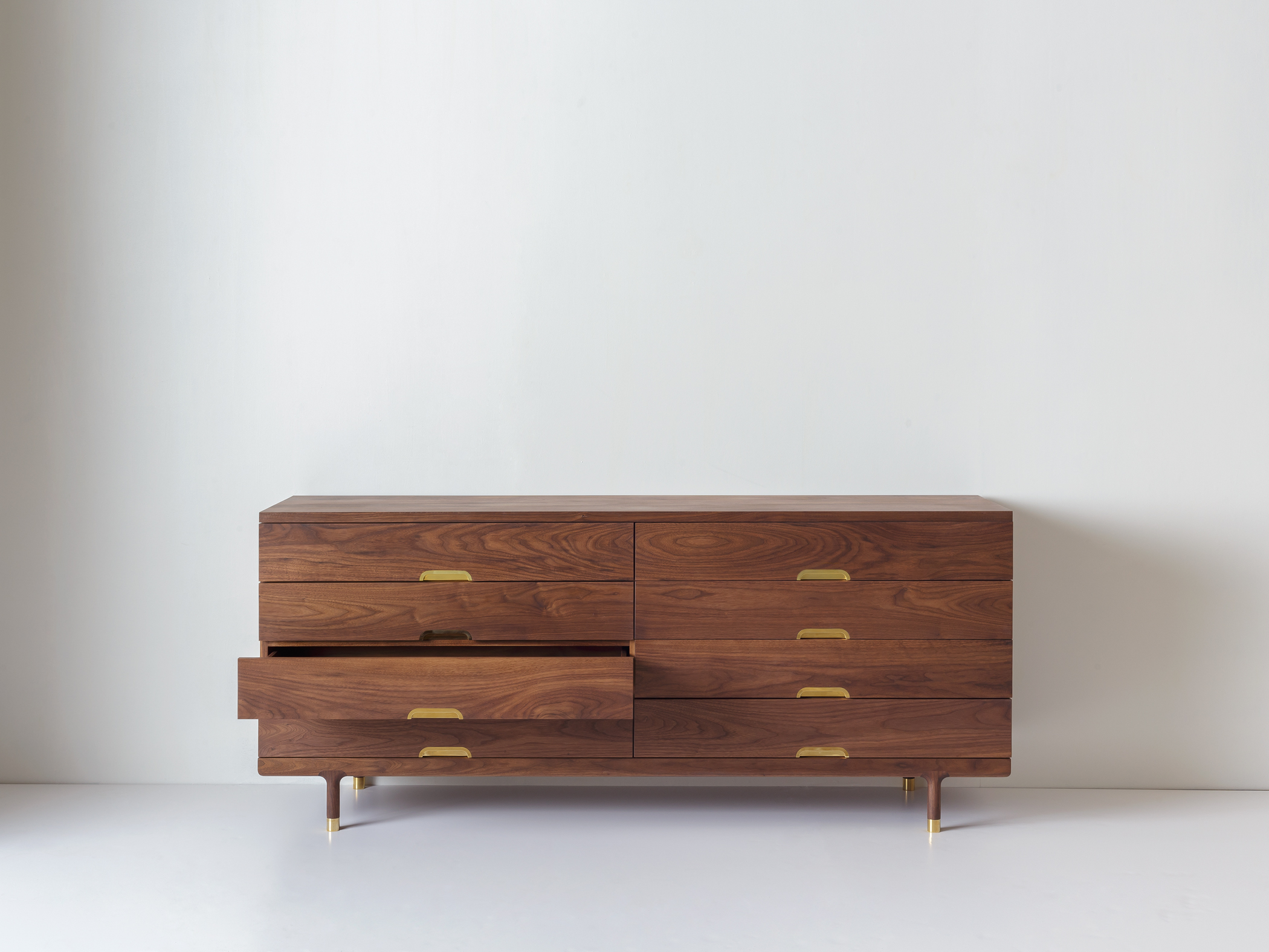 Textured wood grain of the dresser surface with a book and a brass bowl on top.