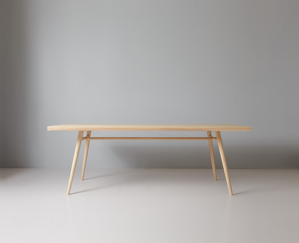 A wooden dining table with a matching bench and stools in a bright room.