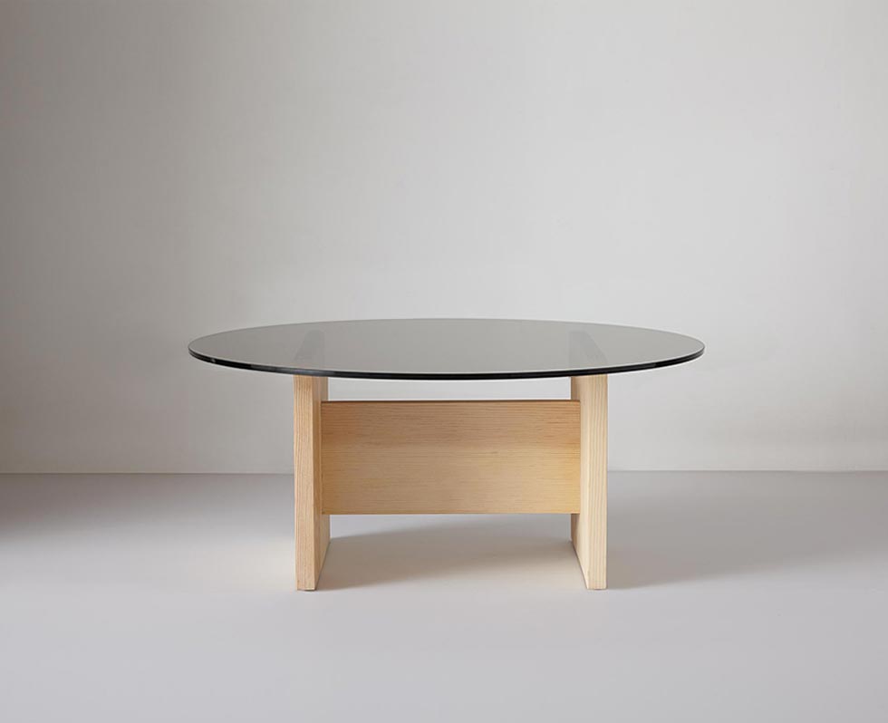 Close-up of round glass tabletop and wooden leg detail of the coffee table