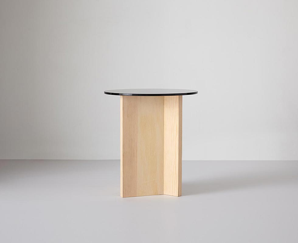 Close-up of a tall round glass table top on a wooden base, with visible joinery