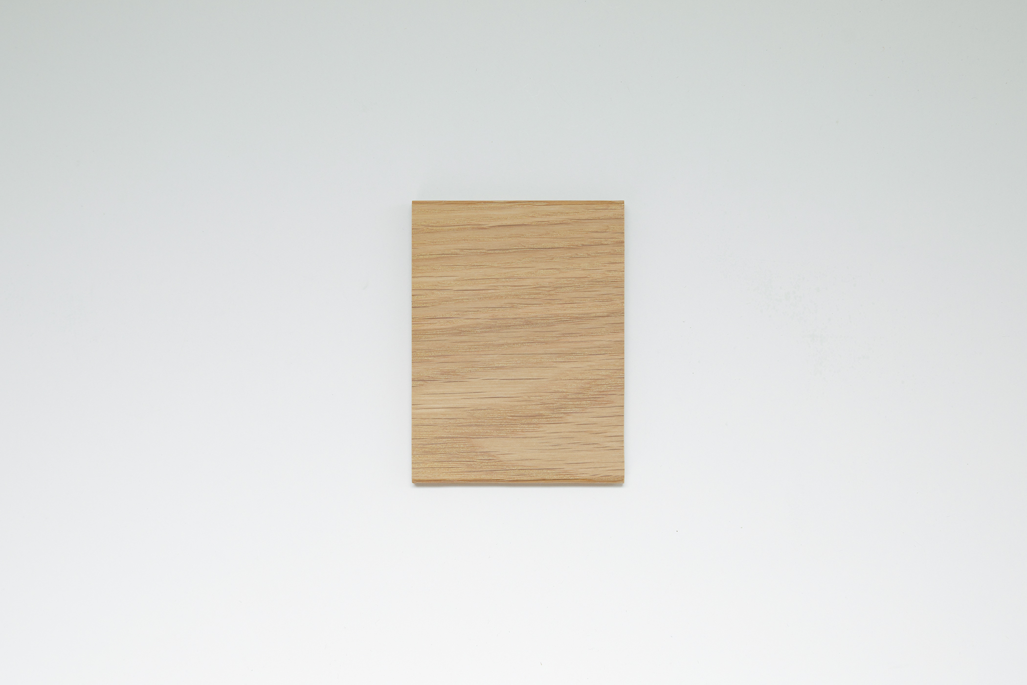 Close-up of a light wood tabletop edge and leg connection, showing joinery and black circular pivot cap.