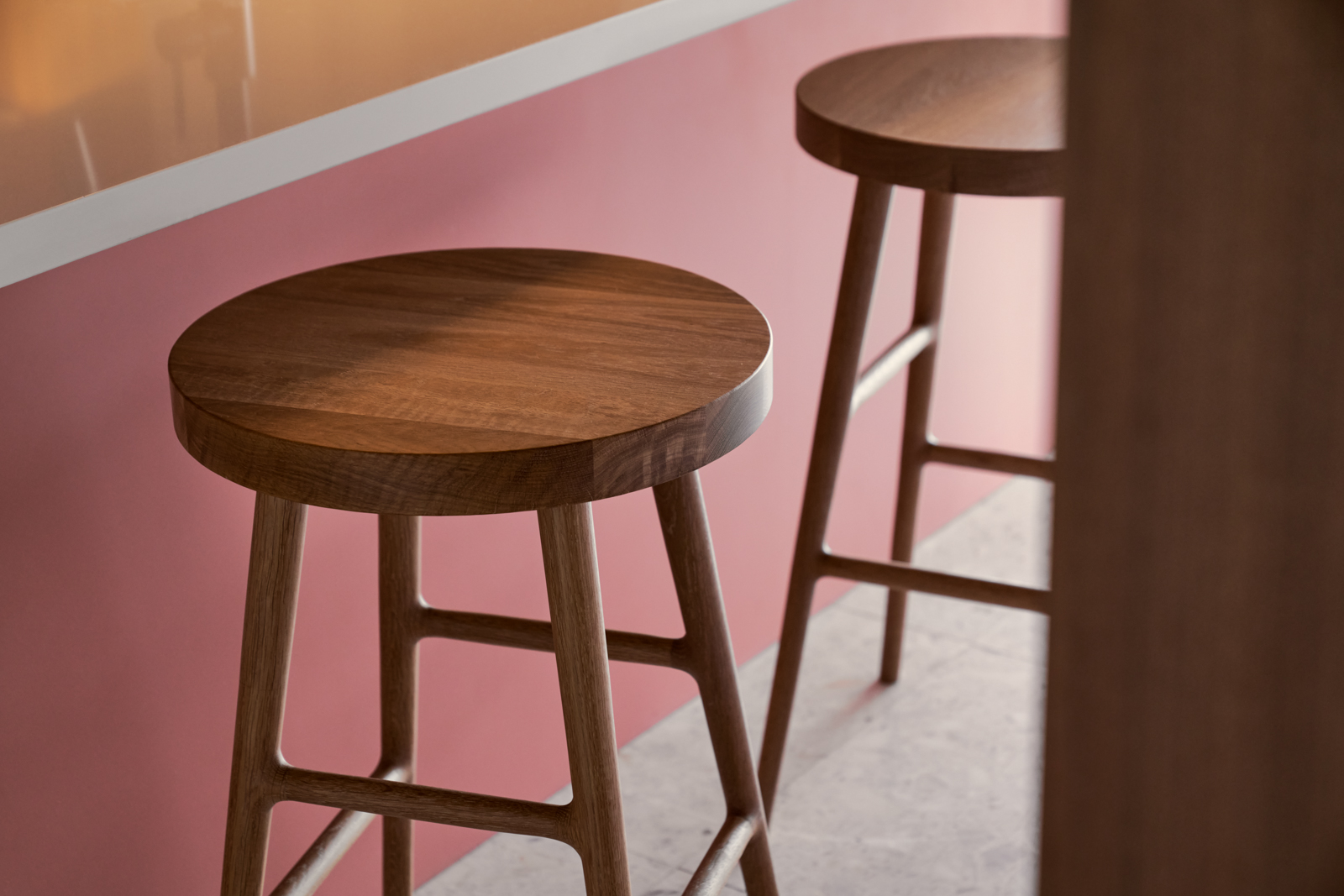 Pink kitchen island with three wooden bar stools, warm lighting
