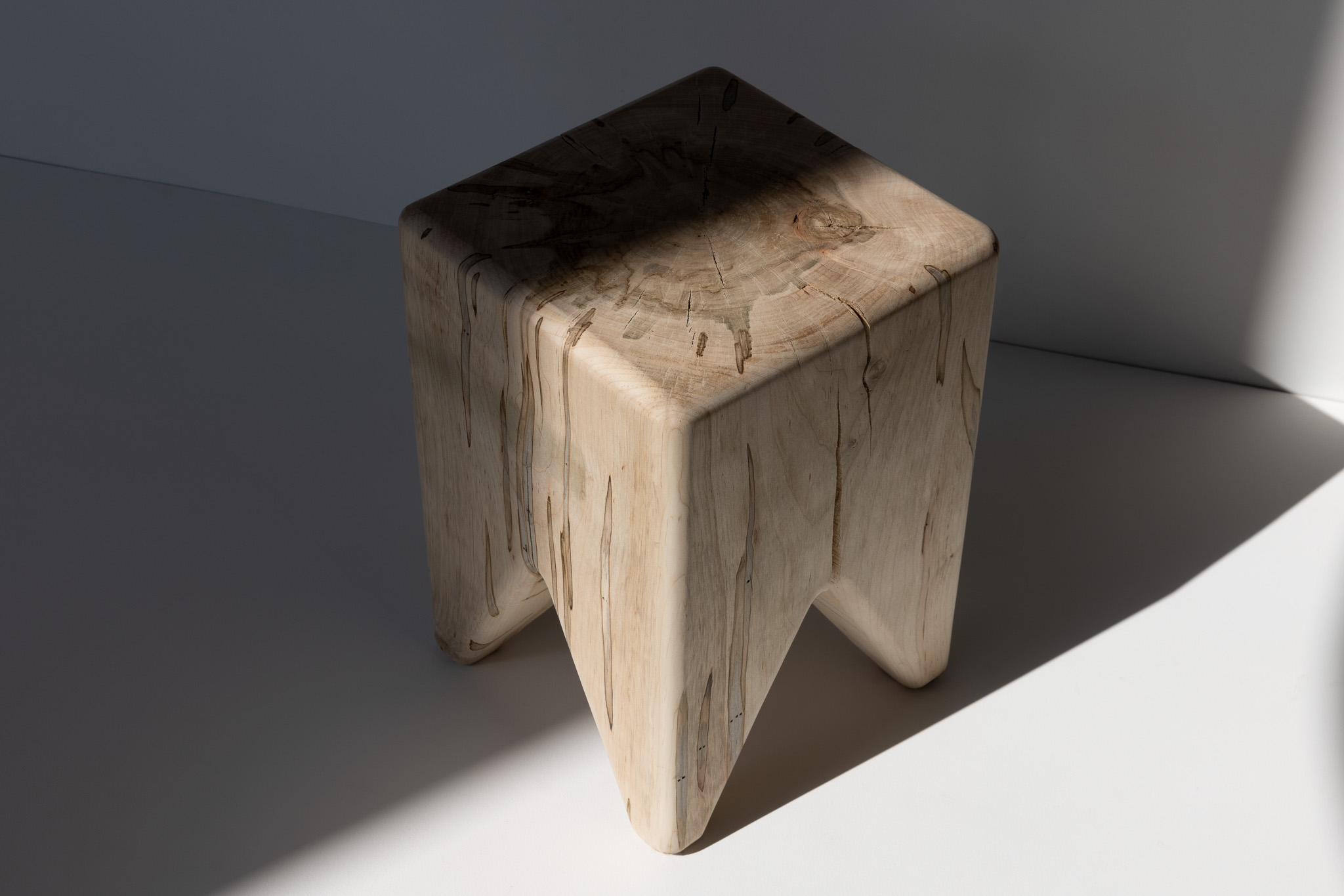 Overhead view of dark-stained version of the same wooden stool with strong shadows