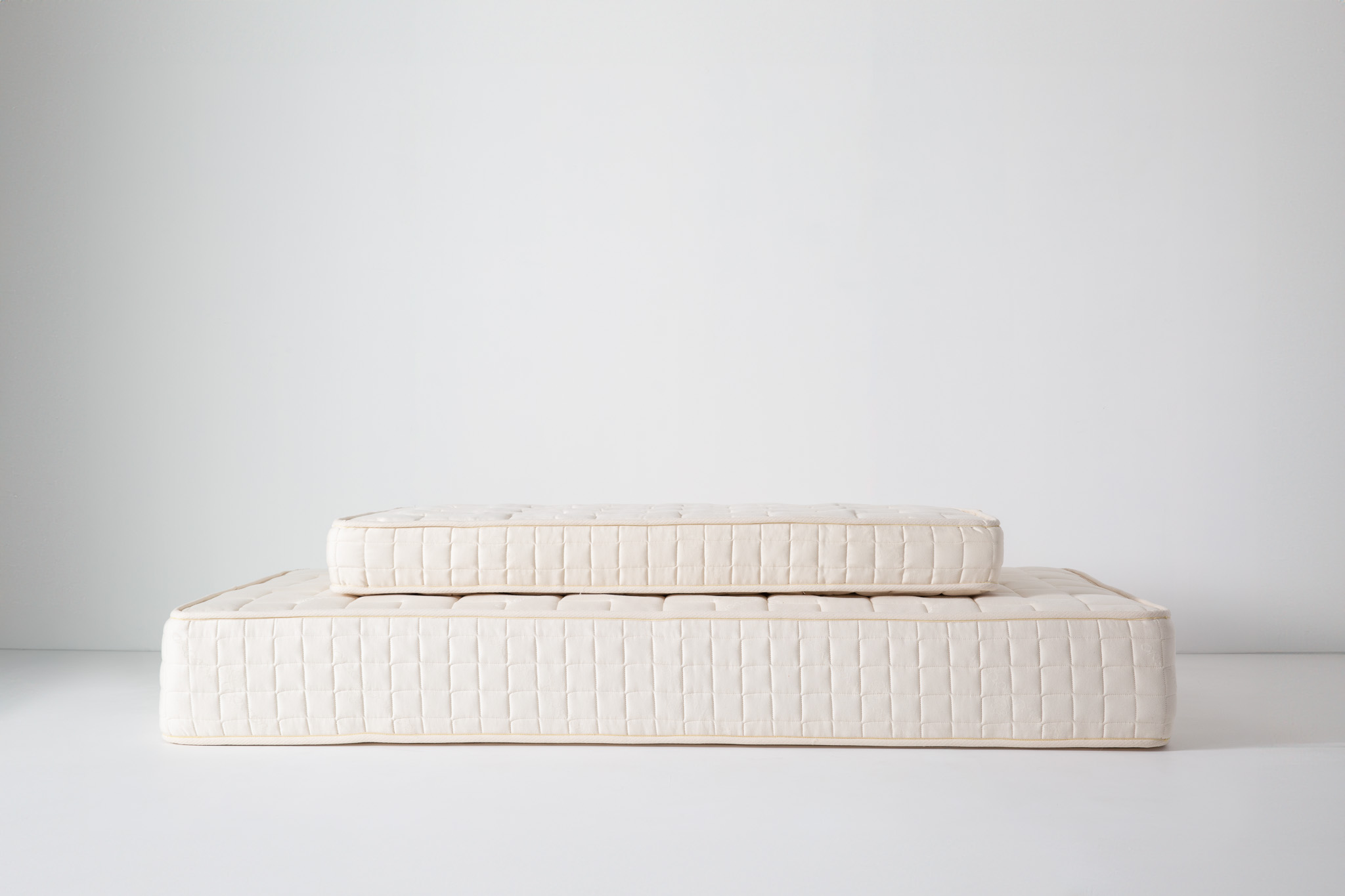 Flat white mattress with pale beige piping along edges