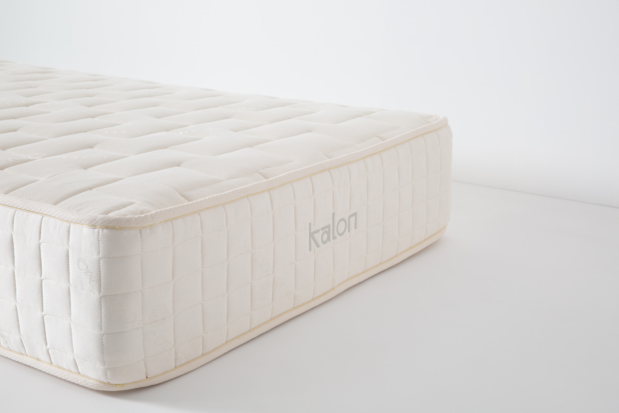 Viewed corner of a padded white mattress showing square quilted pattern