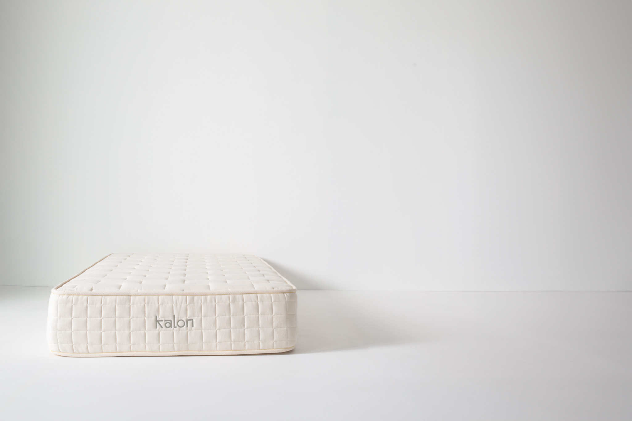Stack of three foam mattress layers with cream quilted covers, showings layers and rough edge on top