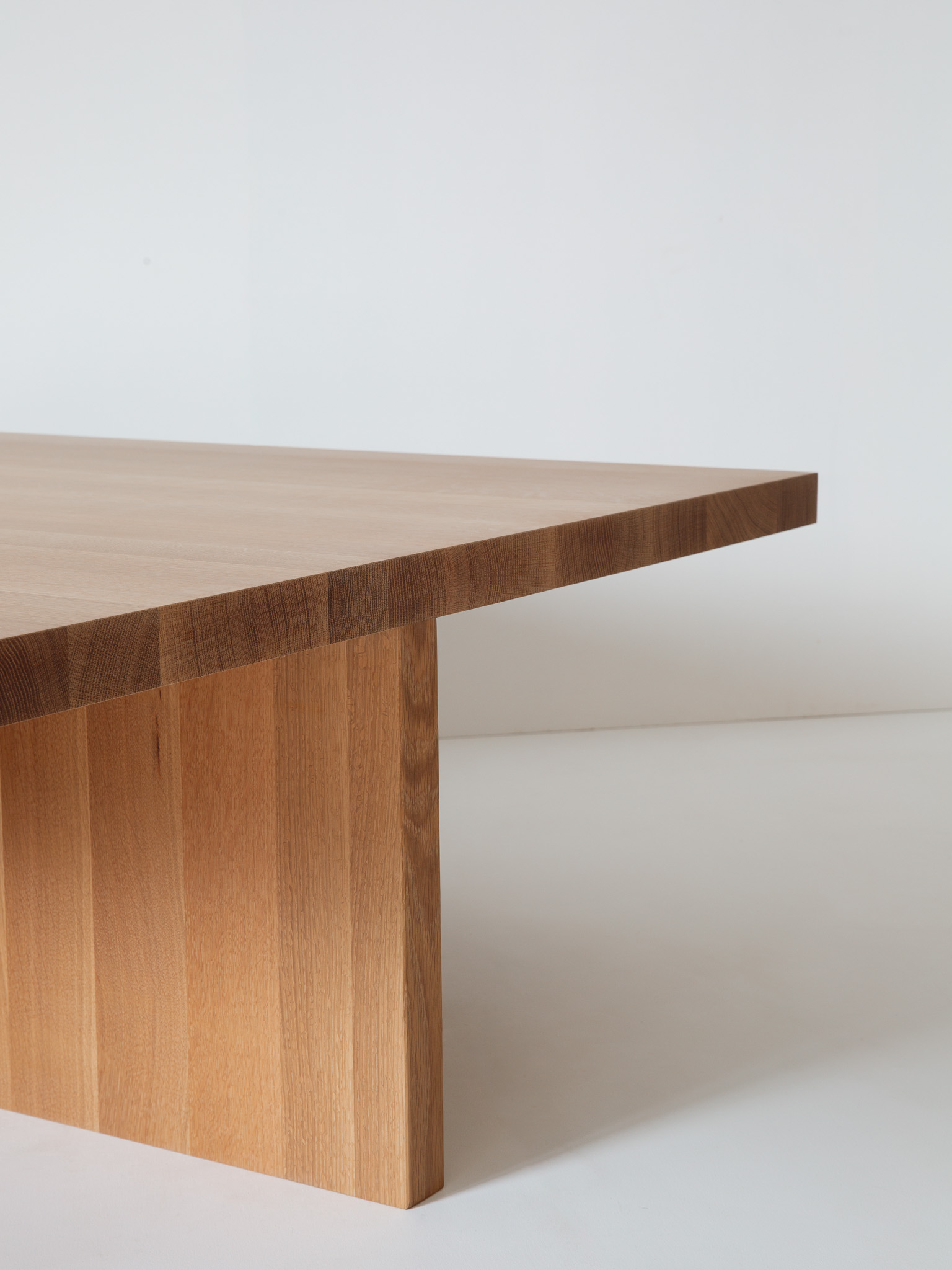 Honey-colored wooden coffee table with three box-like legs and a separate small stool