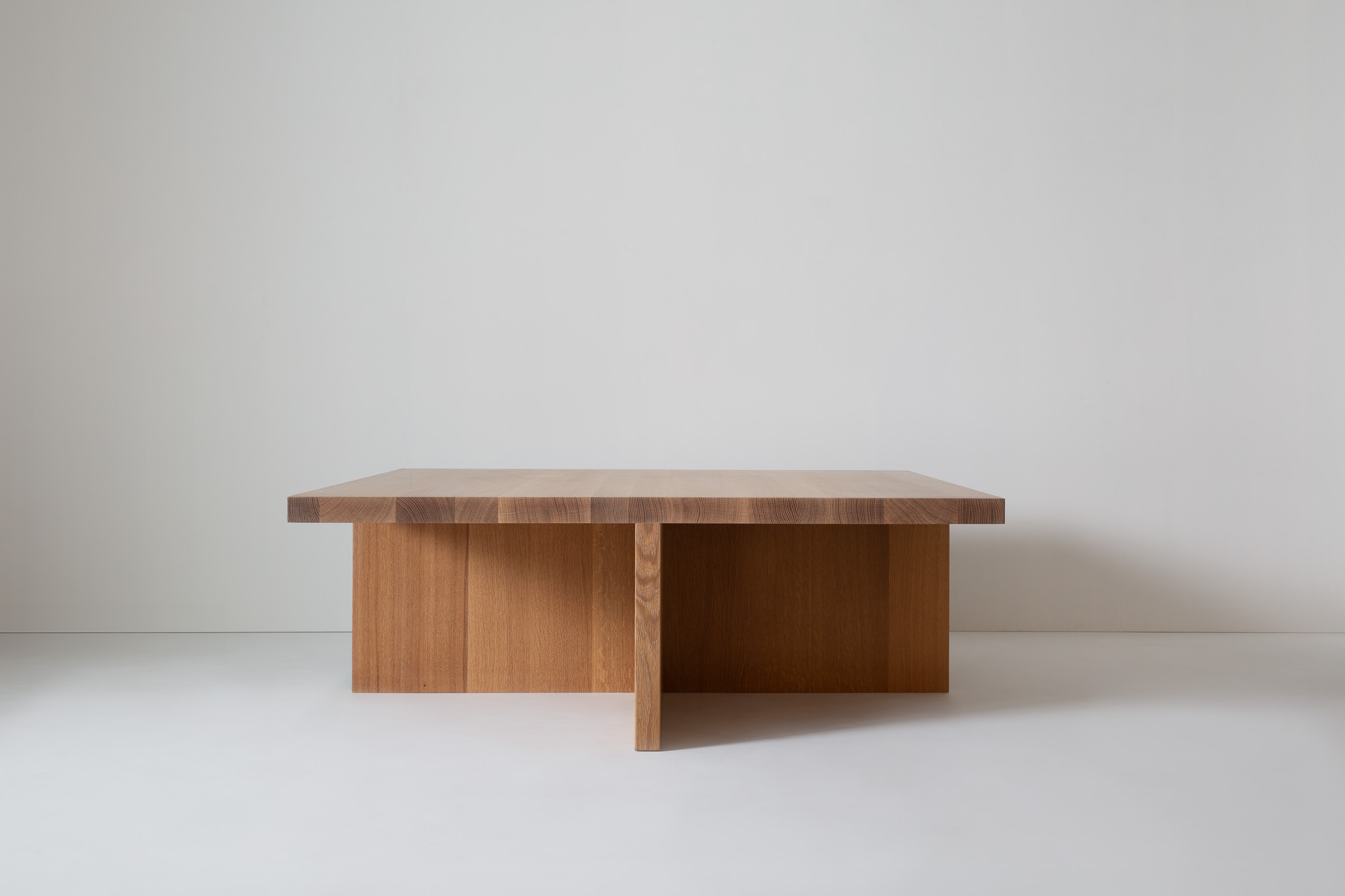 Another view of the wooden table with thick vertical panels as legs forming a geometric base.