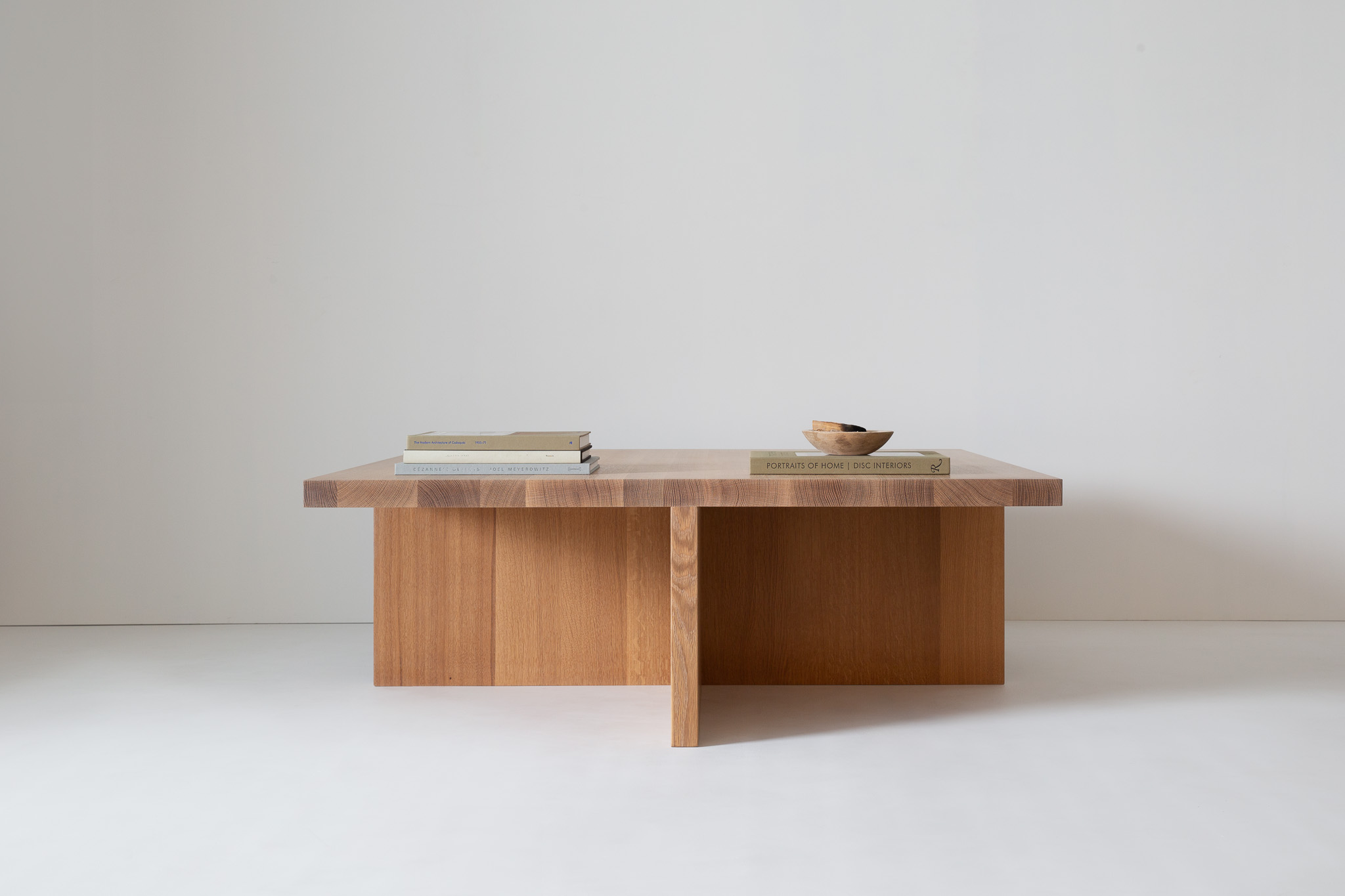 Three wooden cube-shaped stools arranged in a row with a central table, showing uniform wood grain.
