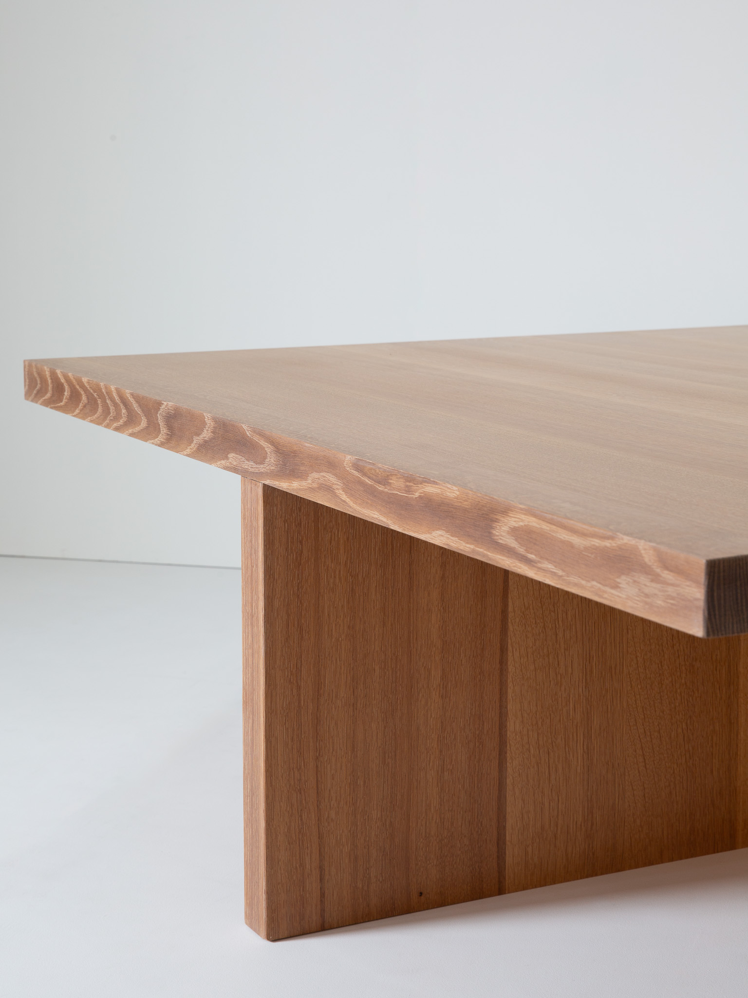 A close-up of the side edge of the table top showing wood grain and beveled edge.