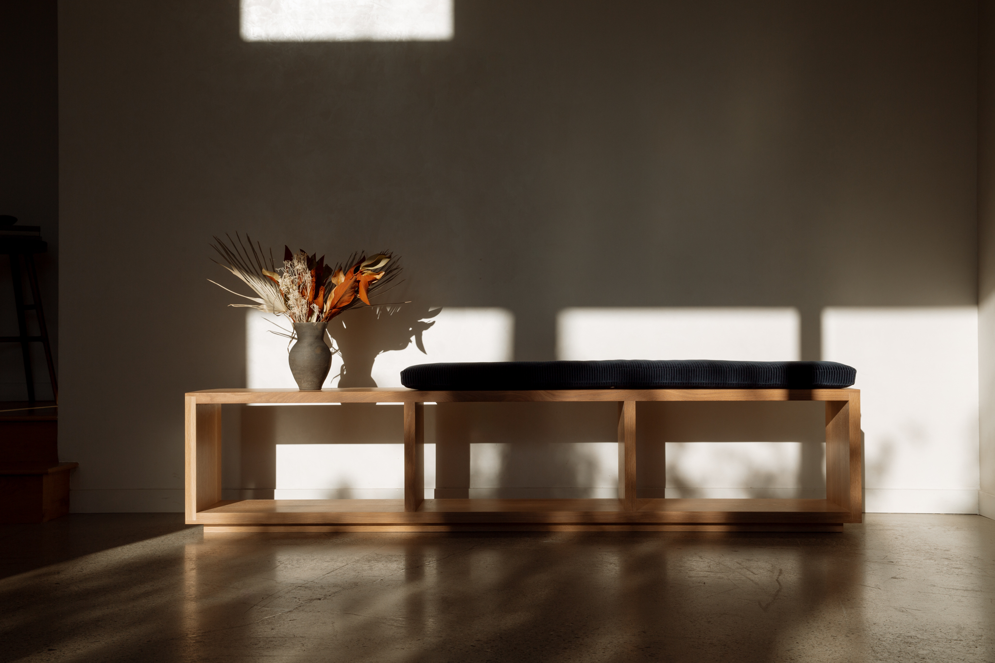 Turntable placed on top of wooden bench with open cuboid sections and vinyl records