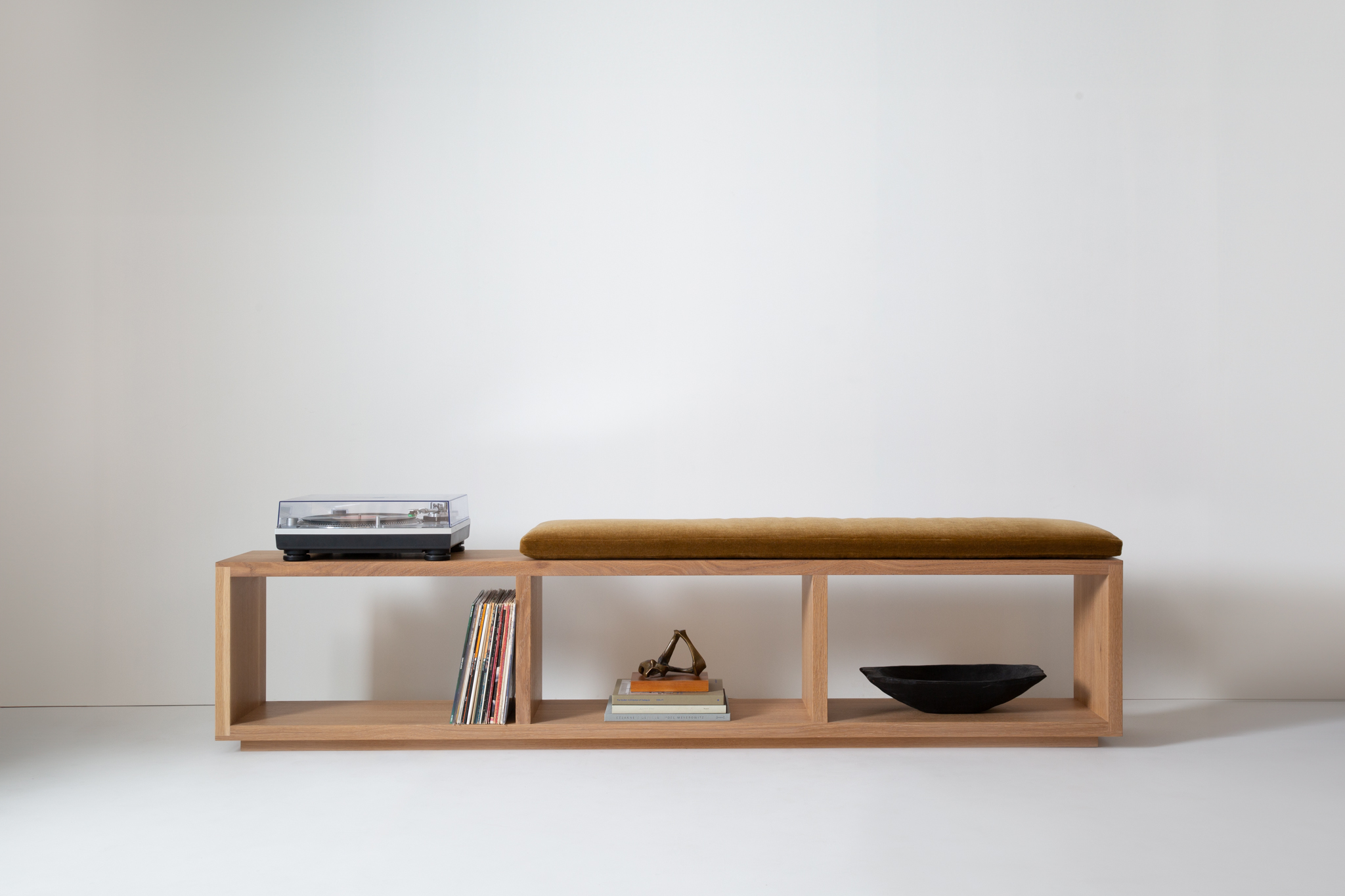 Minimalist wooden bench against plain wall, cushions not present