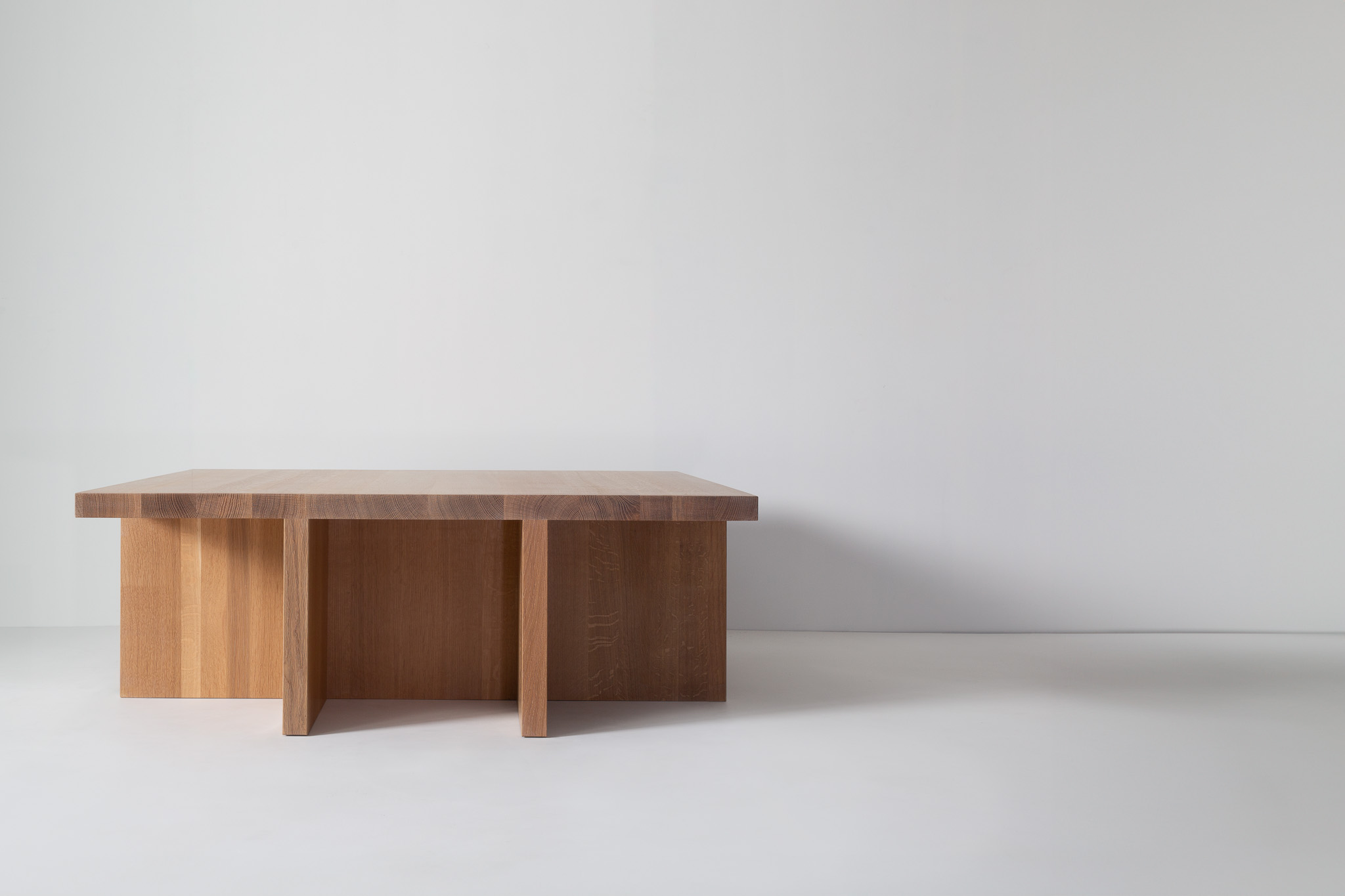 A wooden rectangular coffee table with thick legs and split base, minimal design