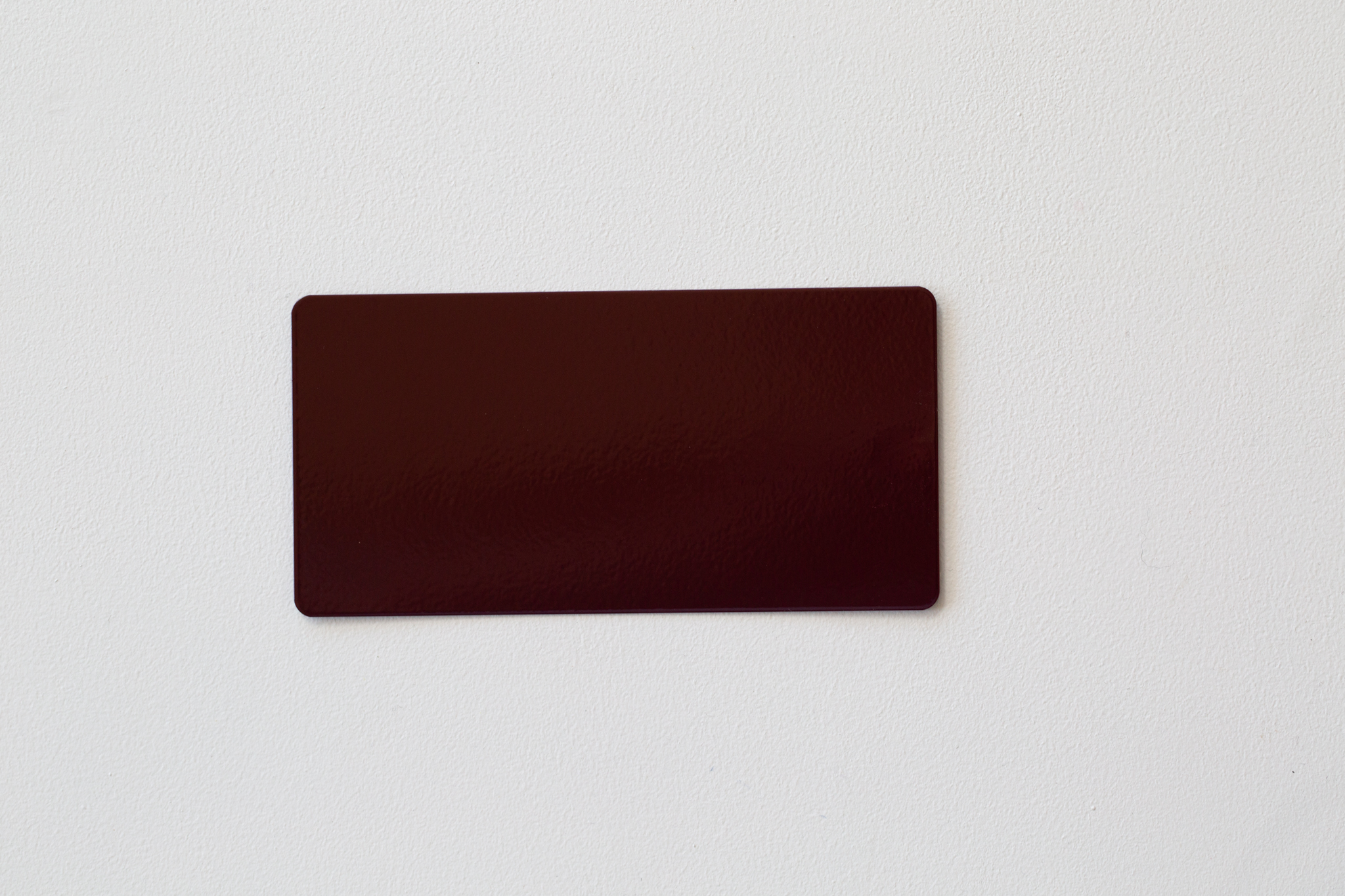 Beige rectangular card or swatch with rounded corners on white wall.